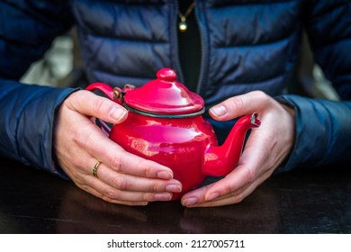 A Red Tea Pot Held In The Hands, Close-up