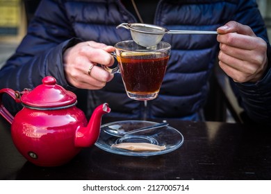 A Red Tea Pot Held In The Hands, Close-up