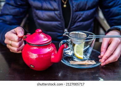 A Red Tea Pot Held In The Hands, Close-up