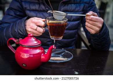 A Red Tea Pot Held In The Hands, Close-up