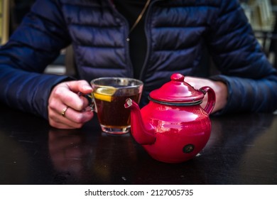 A Red Tea Pot Held In The Hands, Close-up