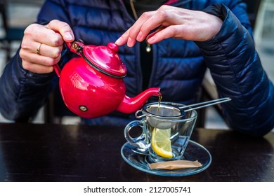 A Red Tea Pot Held In The Hands, Close-up