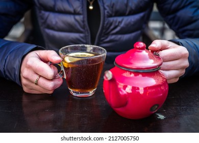 A Red Tea Pot Held In The Hands, Close-up