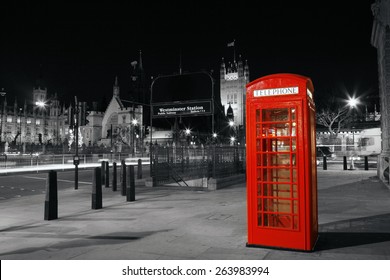 Red Telephone Booth at night, Victoria Tower in the distance. Red phone booth is one of the most famous London icons.