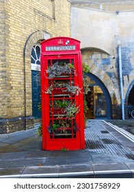 A red telephone booth with plants on it which indicate, in present situatation using telephonebooth is so rare. Which indicates these telephonebooths are going to be abandoned soon for using mobile.