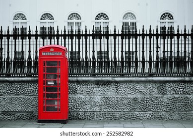 Red telephone box in street with historical architecture in London.