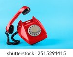 Red telephone with handset on light blue background, space for text