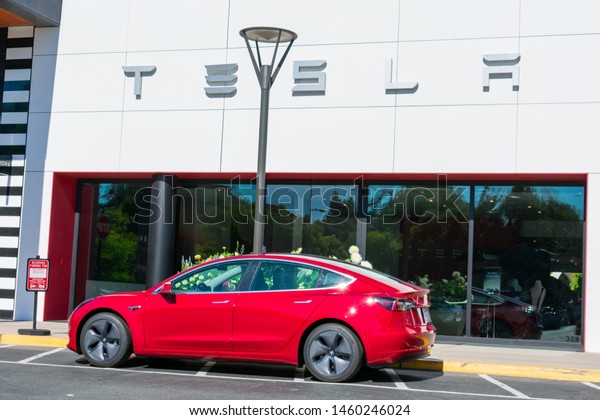 Red Tesla vehicle parked outdoor in front of the\
store in the upscale outdoor shopping center - Palo Alto,\
California, USA - July 23,\
2019