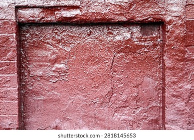Red textured wall surface with old peeling paint and rough masonry structure