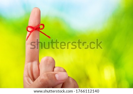 Red thread bow on a human finger