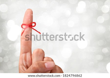 Red thread bow on a human finger