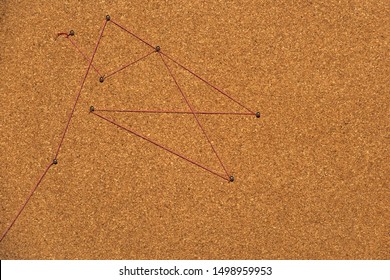 Red Thread Connects Pins On Cork Board From Above