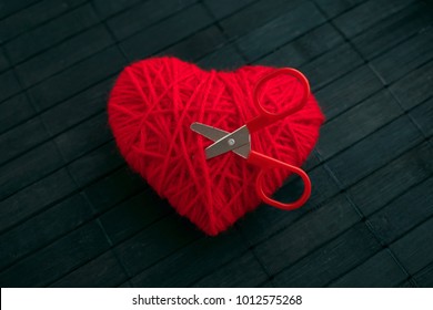 Red Thread Heart With Red Stuck Scissors On Black Wooden  Background. Handmade Heart. Love, Jealousy, Quarrel, Divorce Concept. Selective Focus