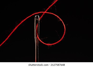 Red Thread And Needle On Black Background.