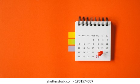 red thumbtacks pointed at the end of month on white calendar  with vivid grunge orange paper background , business or education concept - Shutterstock ID 1931574359