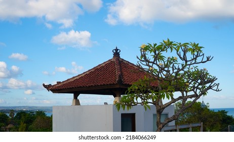 Red tiled gazebo roof against blue sky with white clouds at midday in Bali, Indonesia