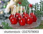 Red toffee candy apples on sticks for sale on farmer market or country fair. Thanksgiving and Halloween homemade red caramel glazed toffee apples with sticks. candies apples on a beautiful plate