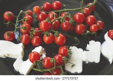 Red tomato cherrys and white cheese on black plate