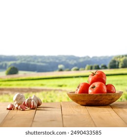 Red tomatoes  and garlic on wooden table with green fields on countryside background. Copy space for products. Cultivating tomatoes vegetables concept and spring and summer garden work time. - Powered by Shutterstock