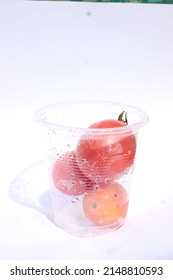 Red Tomatoes In A Plastic Tumbler , White Background