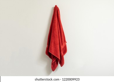 Red towel on a towel hook against a white wall