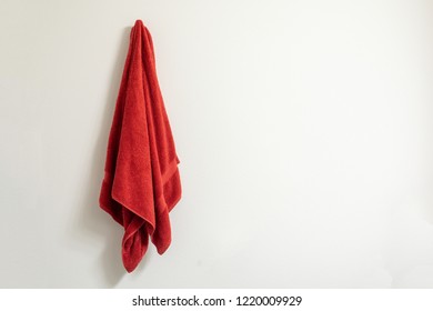 Red towel on a towel hook against a white wall - Powered by Shutterstock