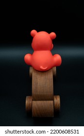 Red Toy Animal Riding On Top Wooden Toy Car Going Away, Wooden Toy Car Made From Cherry Wood, Isolated On A Black Background, Back View, Back Of Car, Concept, Driving, Parking