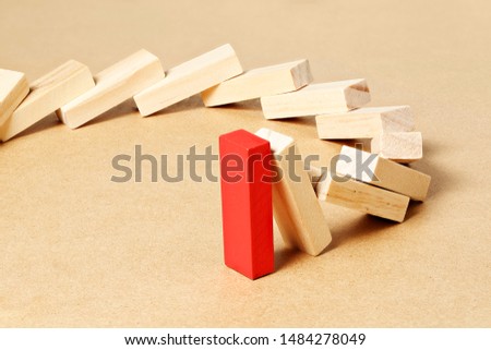 red toy block refusing to fall, abstract leadership or different concept
