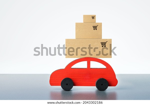 Red\
toy car with boxes on grey background. Home\
delivery.