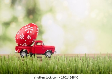 red toy car carrying a decorated easter egg - Shutterstock ID 1901454940