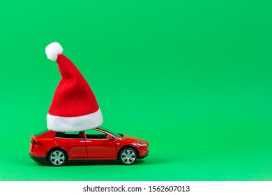 Red Toy Car With Christmas Santa Claus Hat On Light Green Background