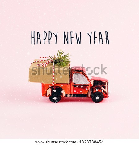 Red toy car delivering Christmas or New Year gift present box on pink background. Copy space
