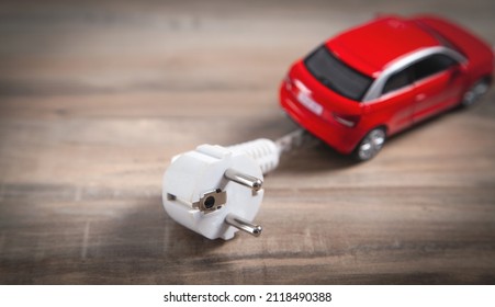 Red toy car with electrical plug. Electric car