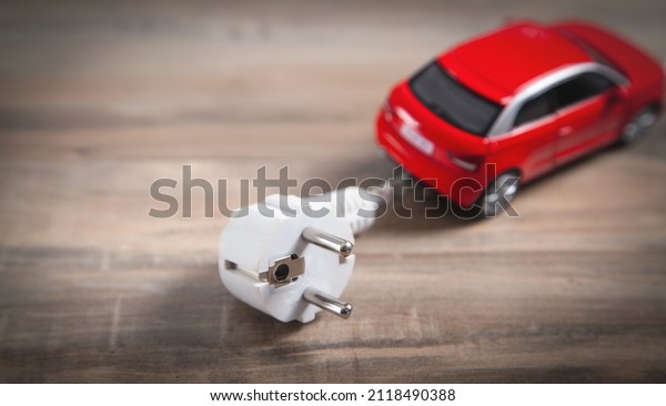 Red toy car\
with electrical plug. Electric\
car