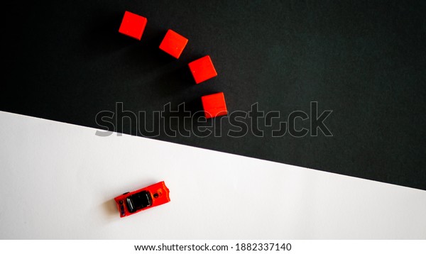 red toy car and four red cubes on black and
white paper background