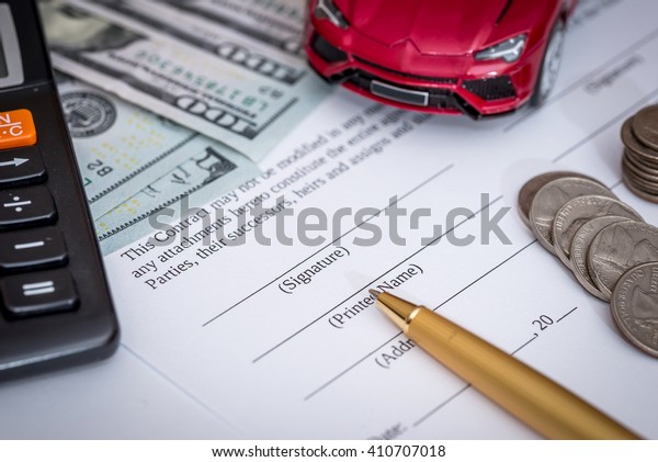 red toy\
car and money on signed contract of car\
sale