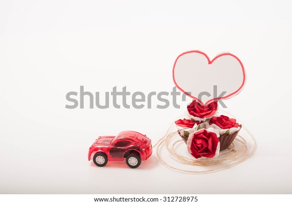 a red toy\
car with roses and a heart-shape\
card