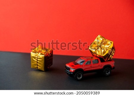 Red toy car SUV gift box on trunk close-up,two-tone black background,levitating festive packaging,bow.New Year,Christmas holiday automobile concept.Dealership prize lottery.Copy space.Auto delivery