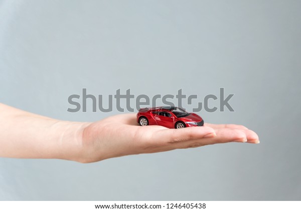Red toy car in woman hand.  rent, insurance and\
buying car concept