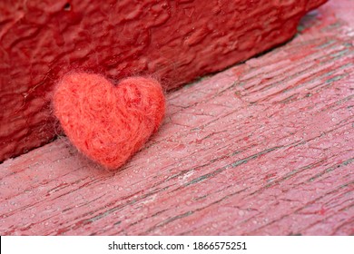 The red toy heart lies on the background of an old wooden surface. A symbol of love, loneliness, melancholy and depression.