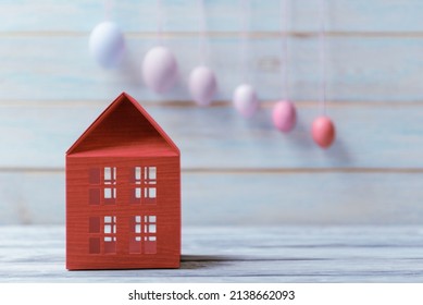 Red Toy House Over Defocused Easter Eggs On Light Wooden Background