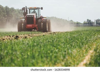 Red Tractor In The Green Field In The Process Of Land Restoration