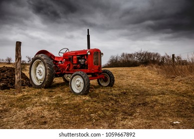 Red Tractor On Field With Dramatic Sky