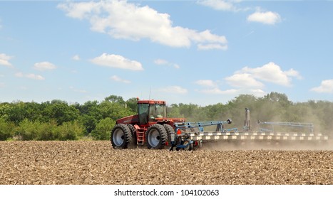 Red Tractor Pulling A Planter In Farm Field