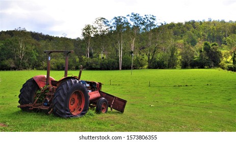 A Red Tractor Sits Forgotten In A Lush, Green Paddock Surrounded By Eucalyptus Trees And Other Australia Bush Landscape