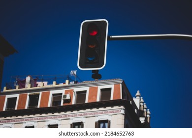 Red traffic light against a background of blue gloomy sky and residential buildings. Urban infrastructure. Regulation of vehicular traffic, traffic on the street. Semaphore lights. Stop and wait sign.