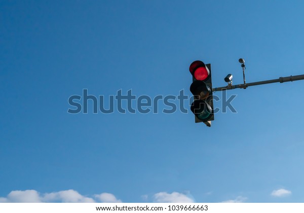 Red traffic light in the city\
street with the beautiful blue sky in the background, copy\
space