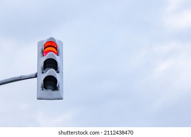 Red traffic light covered with snow and cloudy sky in the background. - Shutterstock ID 2112438470