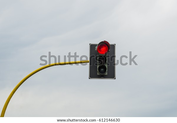 red traffic light  hang against blue sky with\
clouds background. street traffic.\
