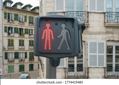 Red traffic light. Image of the red colored figurine of a man. Stop sign for pedestrians. Architecture of ancient city as background.